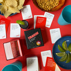 TRAGOS party game on a red table with cards, chips, and drinks.