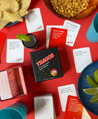 TRAGOS party game on a red table with cards, chips, and drinks.